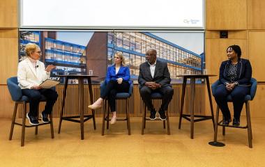 Panel discussion with three speakers and the moderator seated at the front of the room.