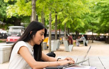 Student on her laptop on Skiles Walkway